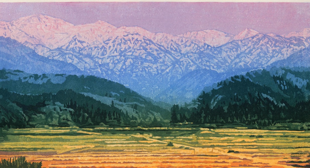 Snow-lit peaks above dark forested ridges, with the ochre stubble of rice terraces spread across the valley floor below.