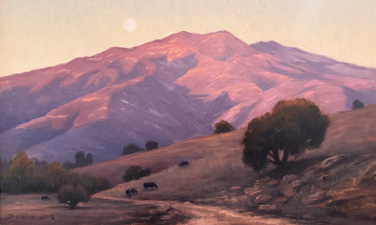 Cattle grazing a dry coastal hillside under a full moon, the range behind it turning rose and violet at last light.